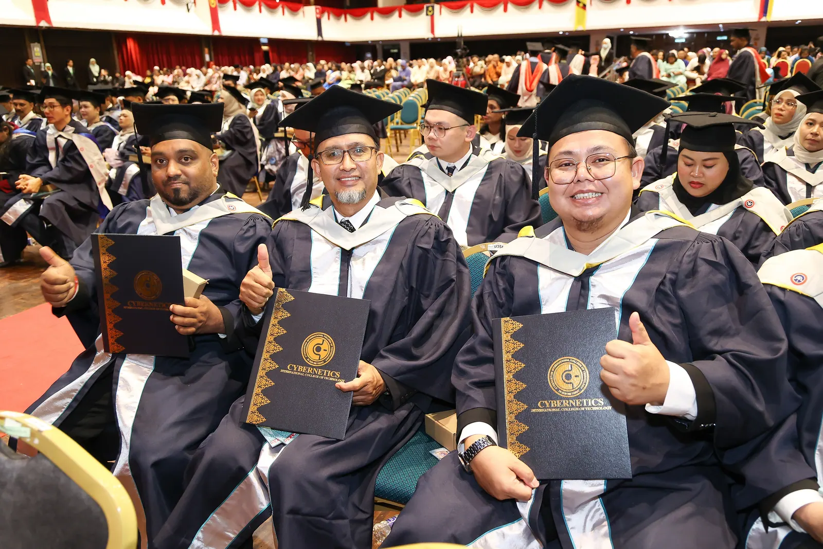 KTAC graduates seated in a convocation hall holding certificate folders